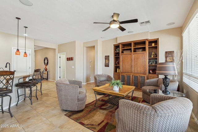living area with ceiling fan, plenty of natural light, light tile patterned floors, and visible vents