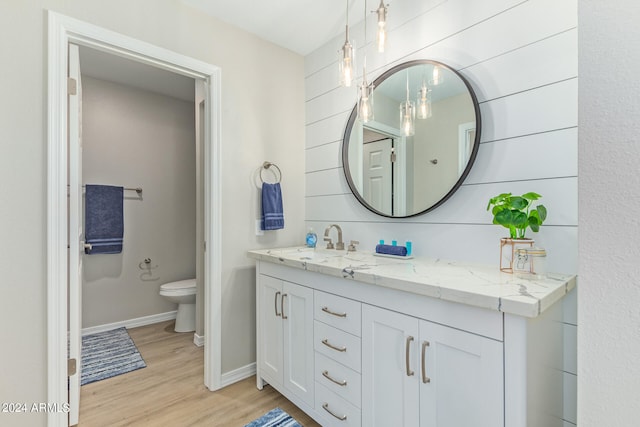 bathroom featuring dual vanity, hardwood / wood-style flooring, and toilet