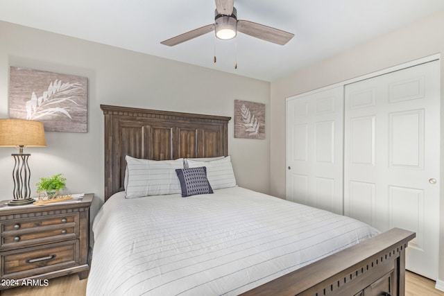 bedroom with a closet, light hardwood / wood-style flooring, and ceiling fan