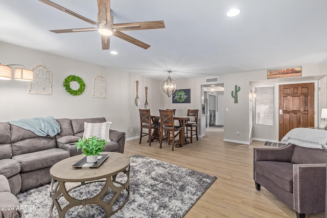 living room with ceiling fan with notable chandelier and light wood-type flooring