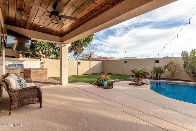 view of patio featuring a grill, a fenced in pool, ceiling fan, and exterior kitchen