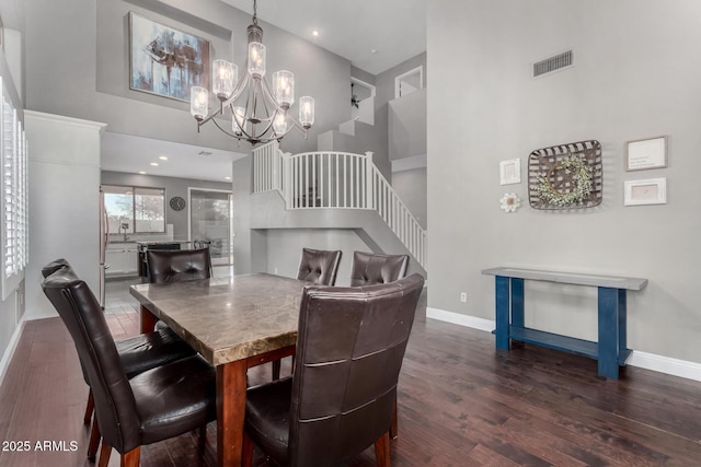 dining area with an inviting chandelier, dark hardwood / wood-style floors, and a high ceiling