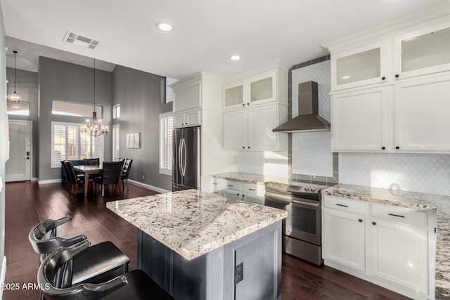 kitchen with white cabinetry, appliances with stainless steel finishes, and wall chimney range hood