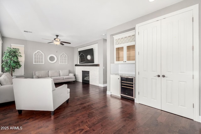 living room with wine cooler, dark hardwood / wood-style flooring, ceiling fan, and bar area