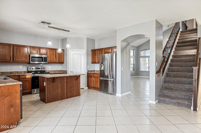 kitchen with light tile patterned flooring, a kitchen breakfast bar, decorative light fixtures, a kitchen island, and stainless steel appliances