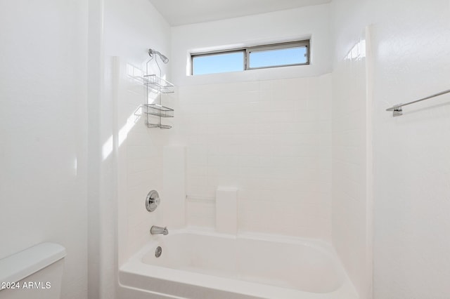 bathroom with toilet and tiled shower / bath