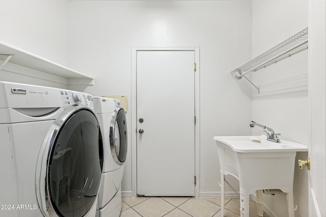 washroom featuring light tile patterned floors, washer and clothes dryer, and sink