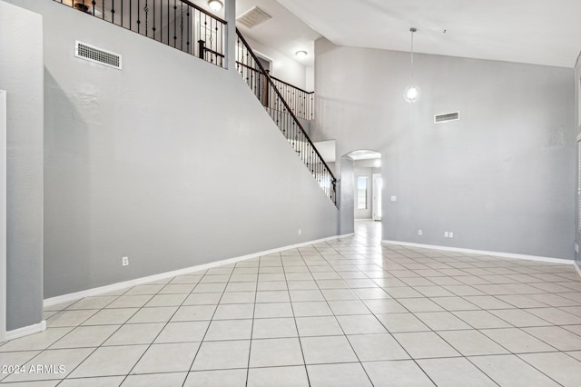 unfurnished living room featuring high vaulted ceiling and light tile patterned flooring