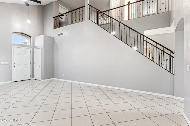 interior space with a towering ceiling, ceiling fan, and light tile patterned flooring