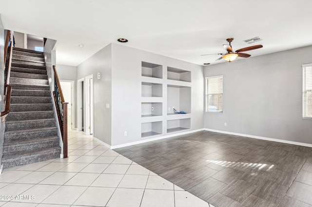 empty room with ceiling fan, light wood-type flooring, plenty of natural light, and built in shelves