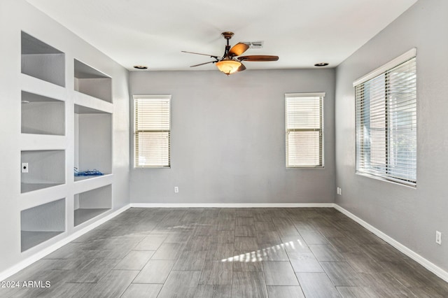 empty room with dark hardwood / wood-style floors, ceiling fan, and built in shelves