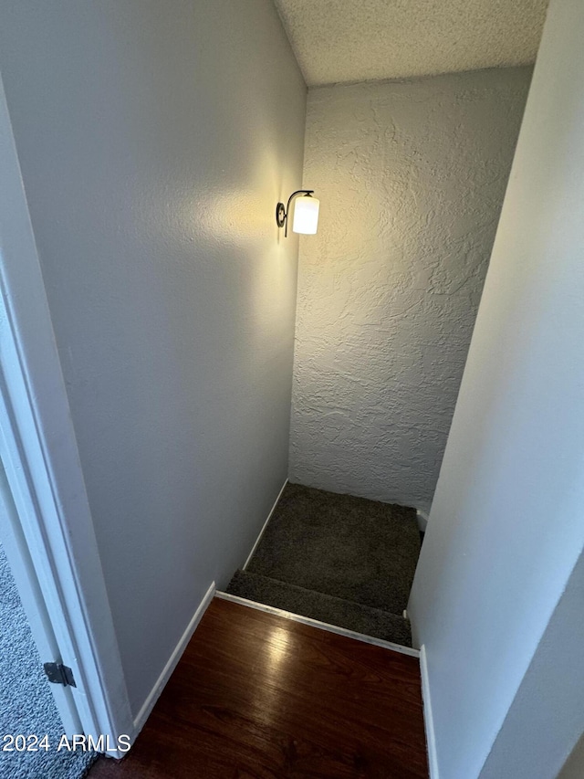 staircase featuring hardwood / wood-style flooring and a textured ceiling