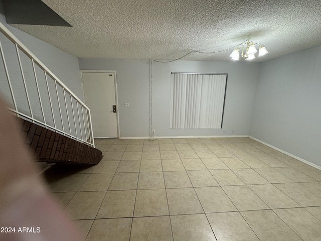 interior space with a notable chandelier, tile patterned floors, and a textured ceiling