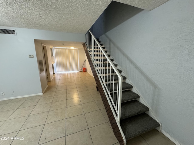 stairway featuring tile patterned floors and a textured ceiling