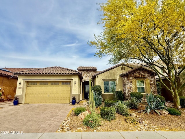 mediterranean / spanish-style house featuring decorative driveway, a garage, a tile roof, and stucco siding