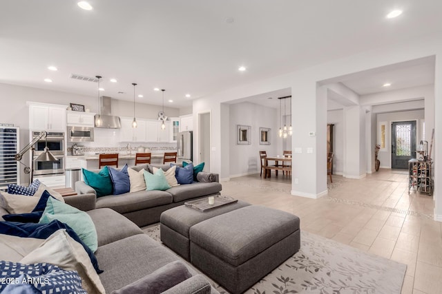 living room with visible vents, an inviting chandelier, baseboards, recessed lighting, and light wood finished floors
