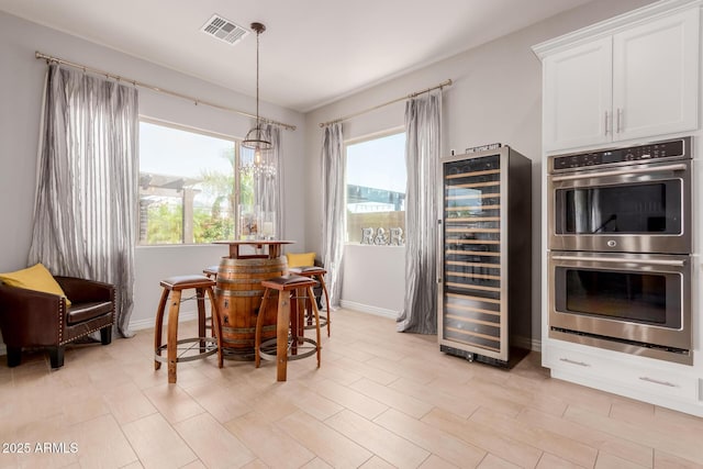 dining room featuring wine cooler, baseboards, plenty of natural light, and visible vents