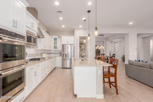 kitchen with a breakfast bar area, backsplash, visible vents, appliances with stainless steel finishes, and a sink