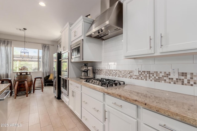 kitchen with visible vents, wall chimney exhaust hood, white cabinets, backsplash, and stainless steel appliances