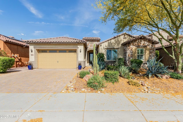 mediterranean / spanish home with a garage, stucco siding, driveway, and a tile roof