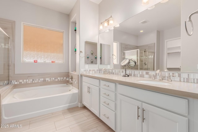 full bathroom featuring a sink, double vanity, a shower stall, and a bath
