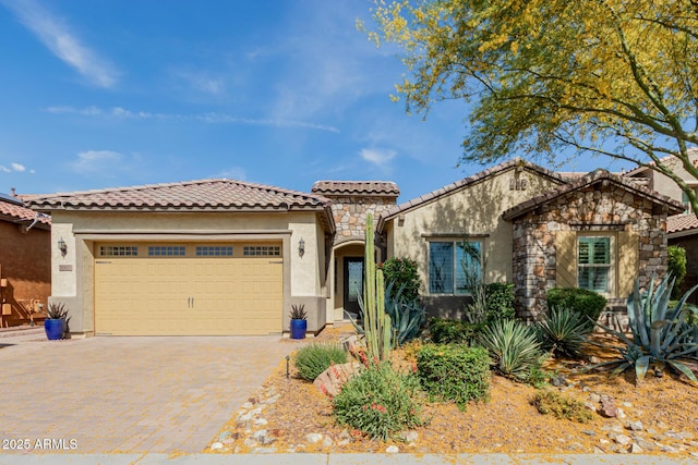 mediterranean / spanish home with a tiled roof, decorative driveway, an attached garage, and stucco siding