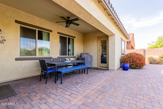 view of patio featuring fence, outdoor dining area, and ceiling fan