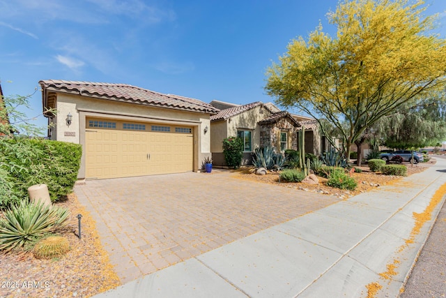 mediterranean / spanish-style house featuring a garage, stucco siding, decorative driveway, and a tile roof