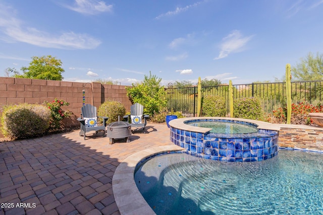 view of swimming pool with a fenced backyard, a patio area, a pool with connected hot tub, and an outdoor fire pit