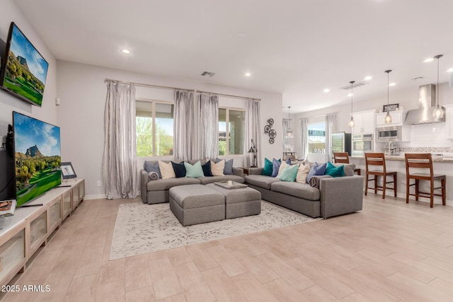 living room featuring recessed lighting, light wood-style flooring, and visible vents
