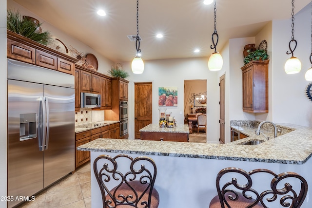 kitchen featuring light stone countertops, sink, hanging light fixtures, kitchen peninsula, and appliances with stainless steel finishes