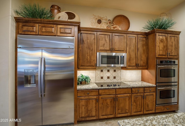 kitchen featuring decorative backsplash, light stone countertops, and stainless steel appliances