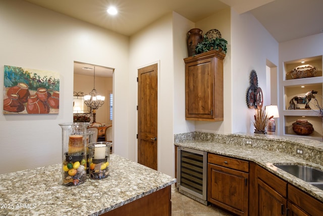 kitchen with sink, wine cooler, light stone counters, a notable chandelier, and light tile patterned floors