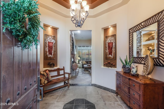 entryway featuring a chandelier, light tile patterned floors, and a tray ceiling