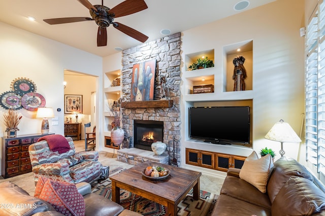 living room featuring built in features, ceiling fan, and a stone fireplace