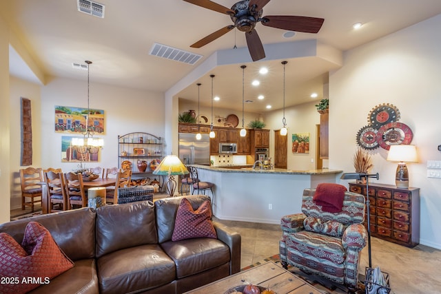 tiled living room with ceiling fan with notable chandelier