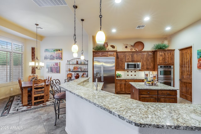 kitchen featuring pendant lighting, a kitchen breakfast bar, a spacious island, a notable chandelier, and stainless steel appliances