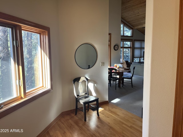 corridor featuring light hardwood / wood-style flooring, wooden ceiling, and vaulted ceiling