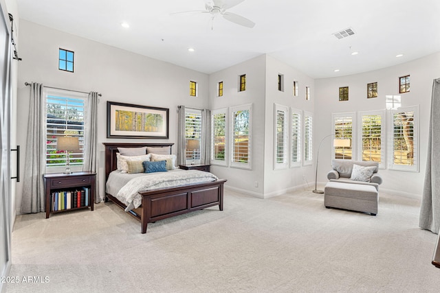 carpeted bedroom featuring ceiling fan and a high ceiling