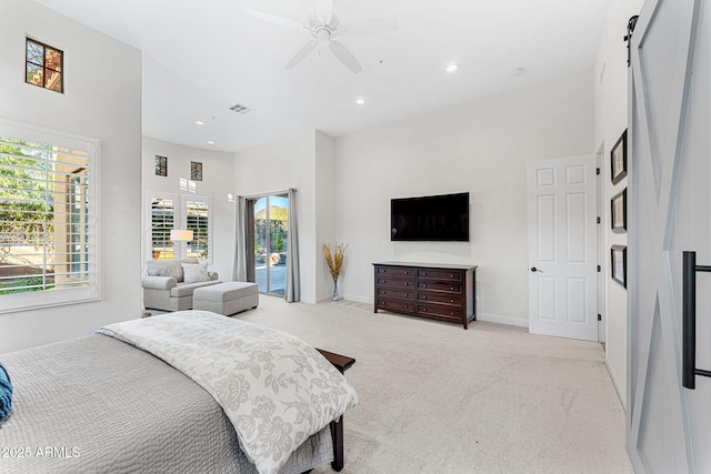 carpeted bedroom with ceiling fan, a towering ceiling, a barn door, and access to exterior