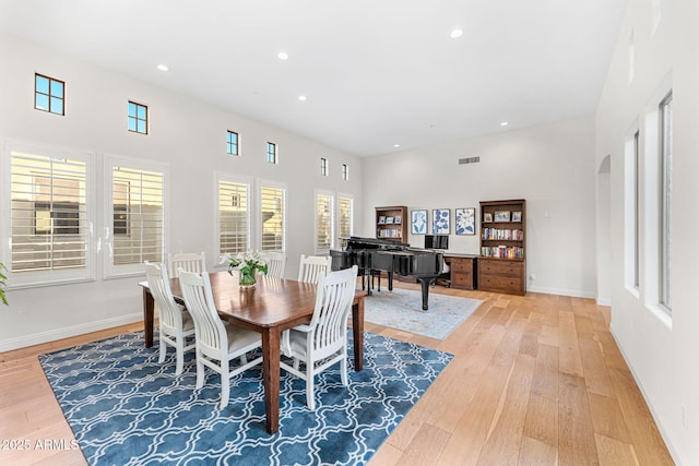 dining area featuring a healthy amount of sunlight, a high ceiling, and light wood-type flooring