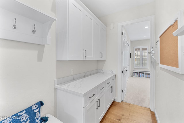 interior space with light stone counters, light hardwood / wood-style flooring, and white cabinets