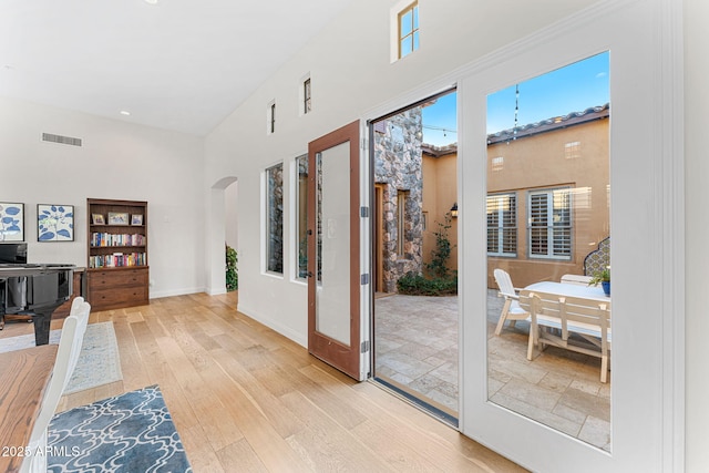 doorway featuring a towering ceiling, light hardwood / wood-style floors, and french doors