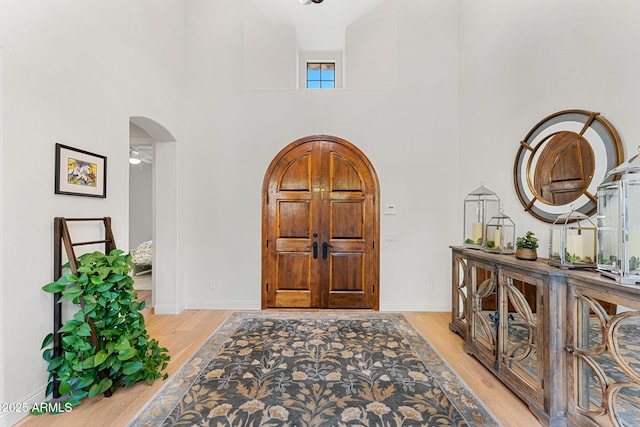 entryway featuring a towering ceiling and light hardwood / wood-style flooring