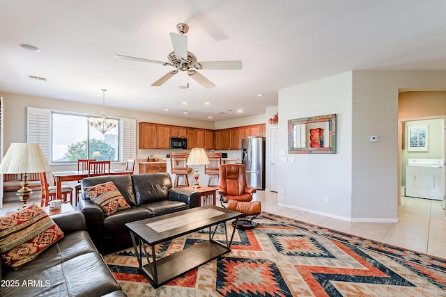 living room featuring ceiling fan with notable chandelier, washer / dryer, and light tile patterned floors