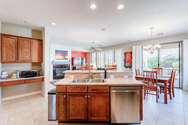 kitchen with stainless steel dishwasher, hanging light fixtures, sink, and a kitchen island with sink