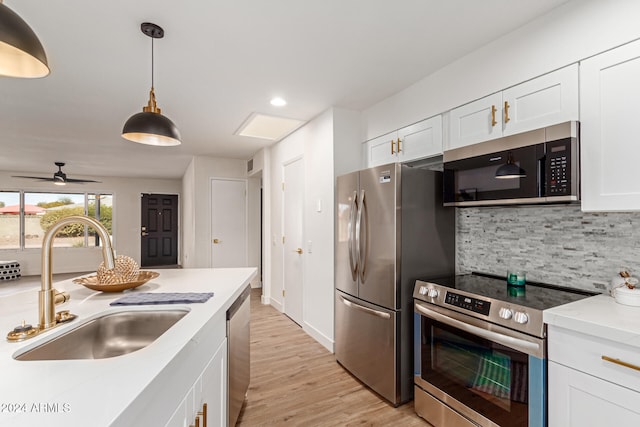 kitchen with appliances with stainless steel finishes, light hardwood / wood-style flooring, white cabinetry, and sink