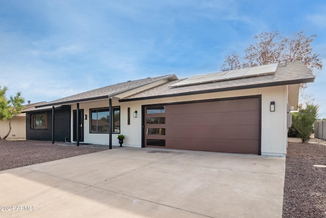 ranch-style home featuring solar panels and a garage