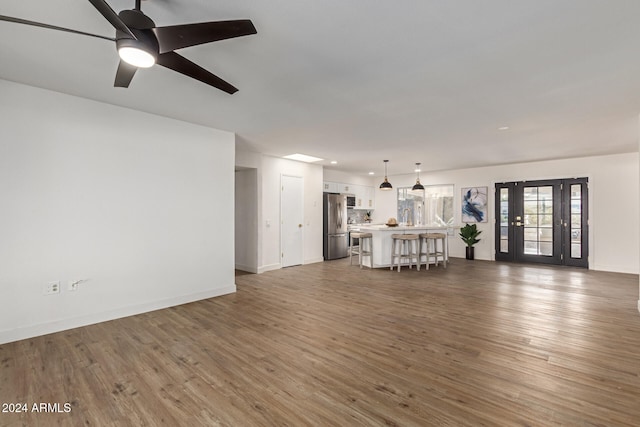 unfurnished living room featuring ceiling fan and dark hardwood / wood-style flooring