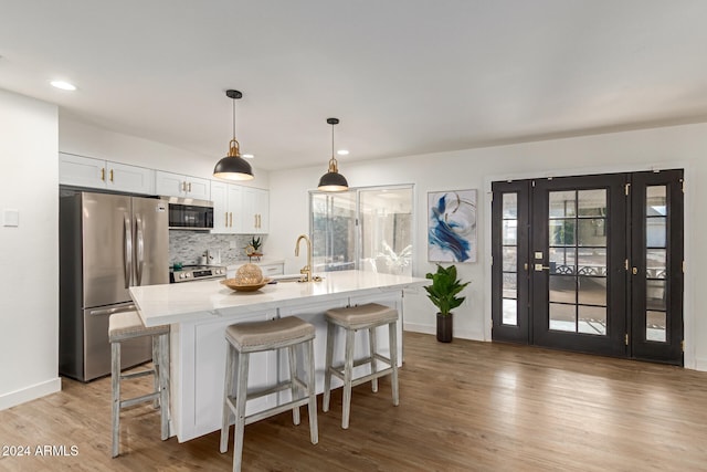 kitchen featuring white cabinetry, hardwood / wood-style flooring, stainless steel appliances, and pendant lighting